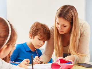 Kind und Lehrerin an Schulbank